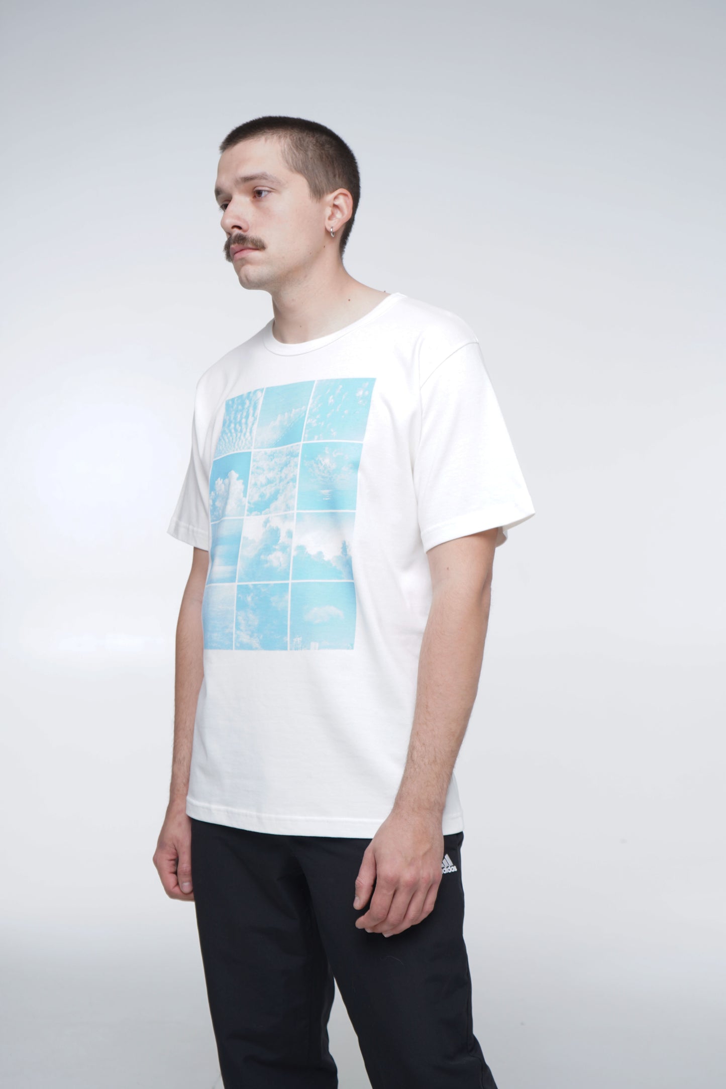 Person wearing a white t-shirt with a blue graphic design on a plain background