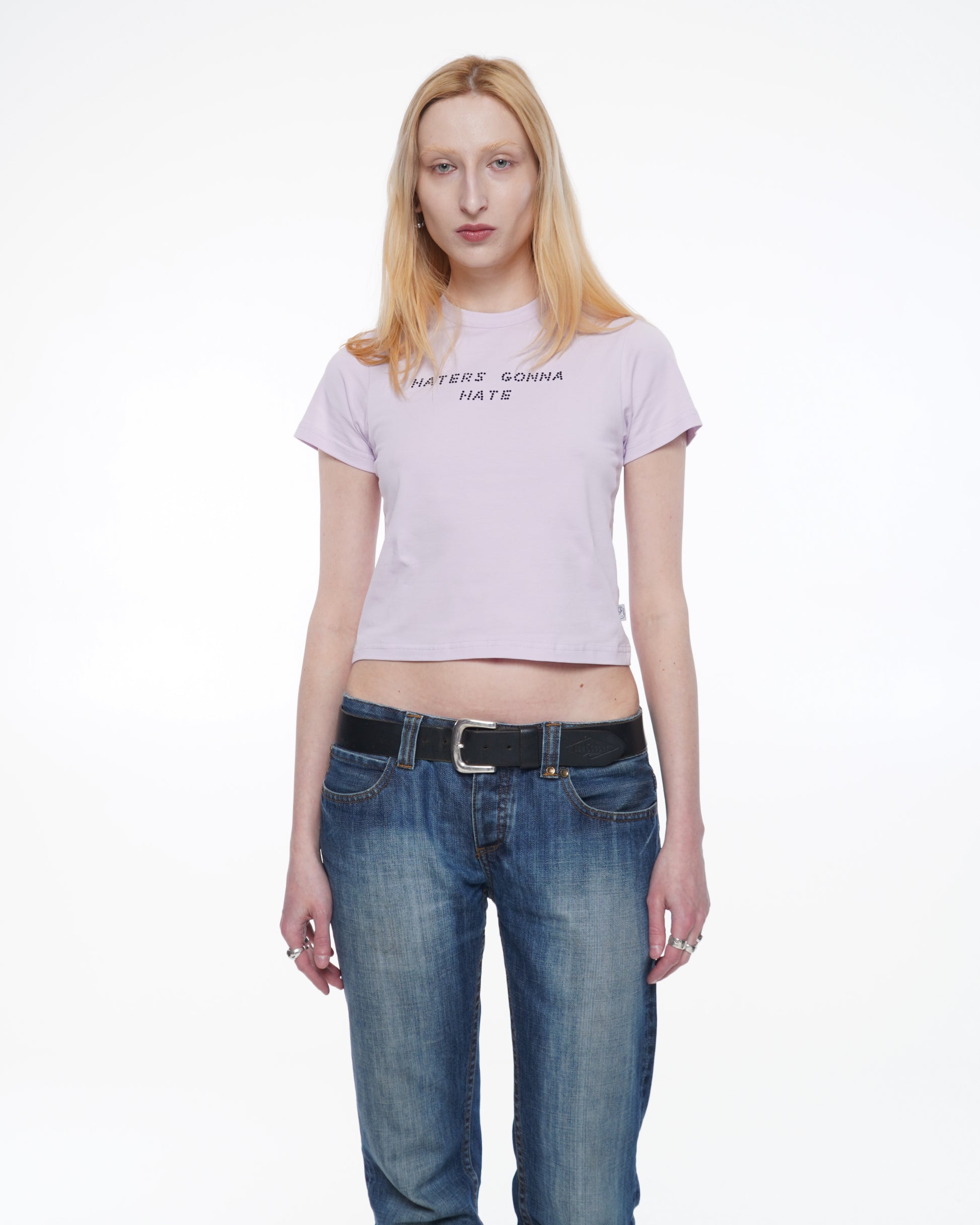 Person wearing a Light pink stretchy cotton baby T-shirt with a fitted silhouette and black rhinestone text "haters gonna hate"