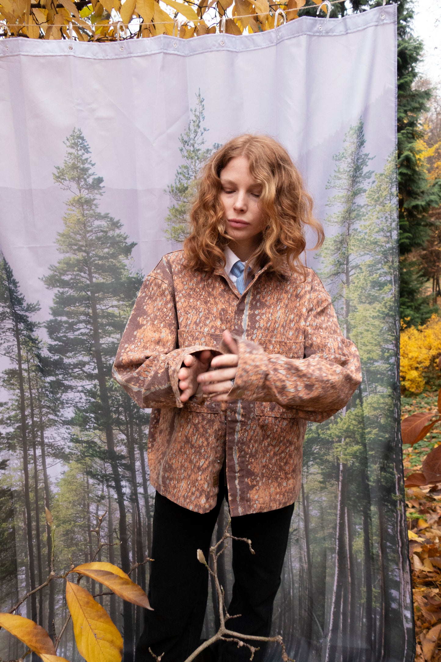 Person wearing a patterned jacket standing in front of a forest backdrop
