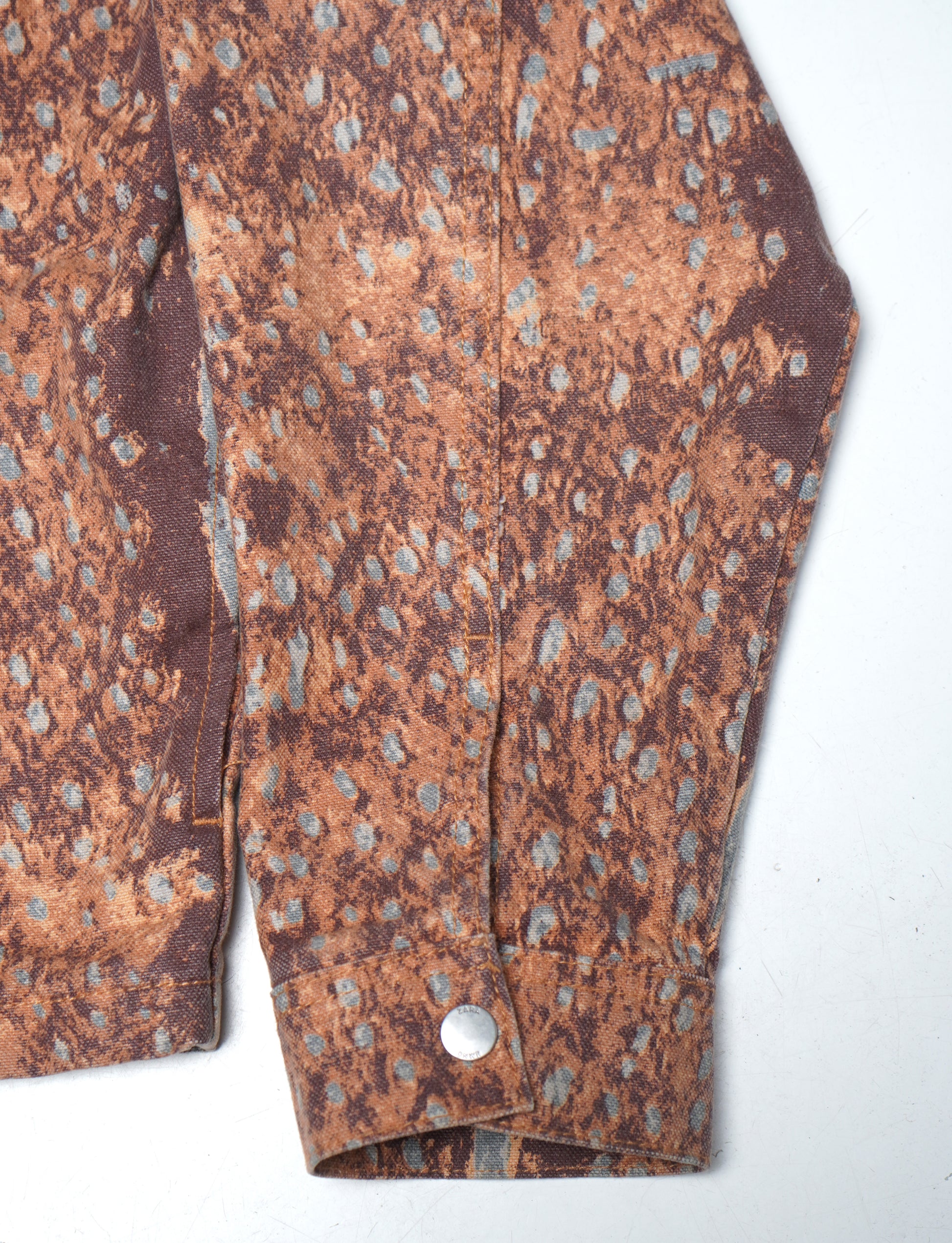 Close-up of a patterned fabric with a button on a white background