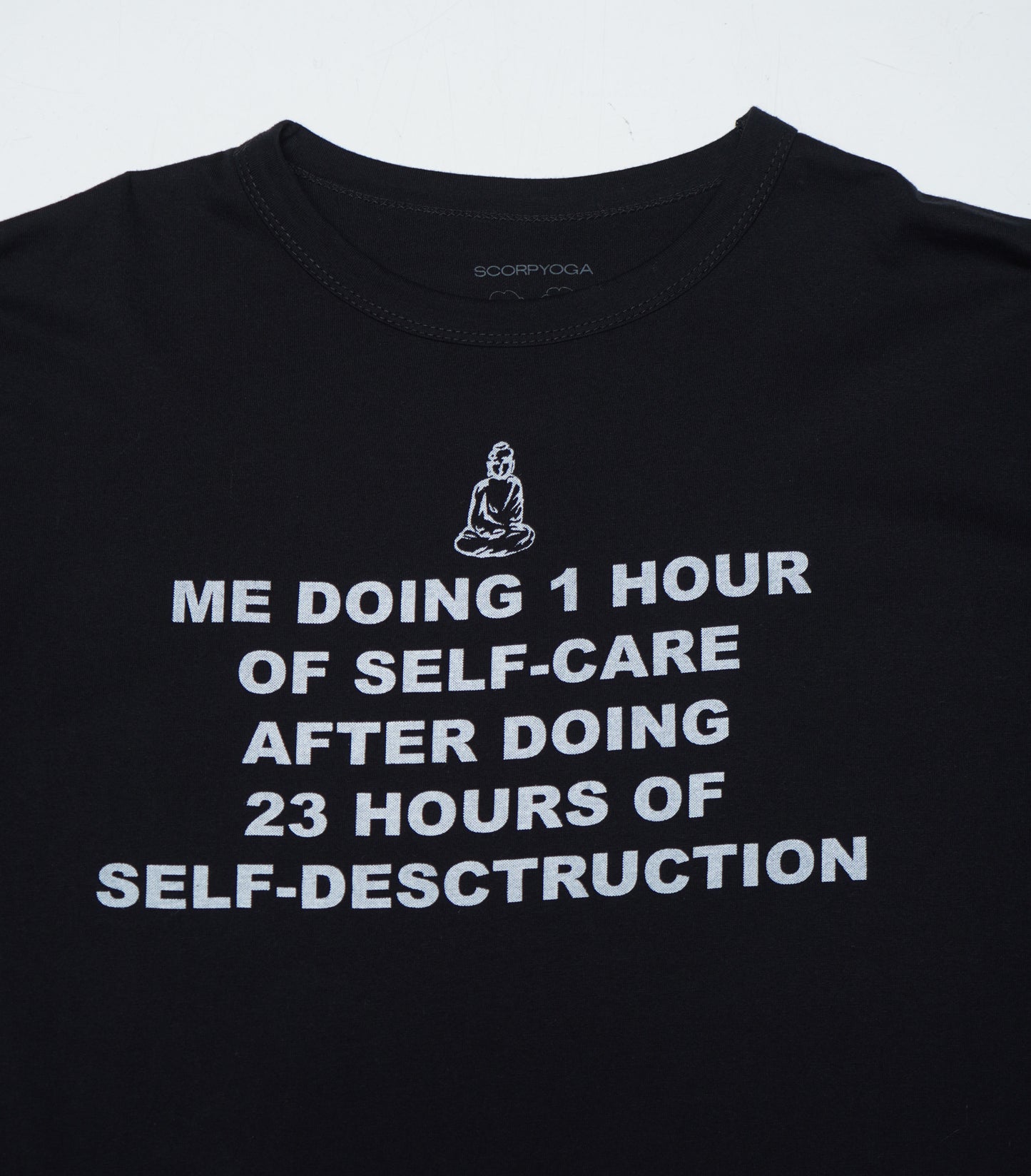 Black t-shirt with white text and a Buddha illustration on a light gray background