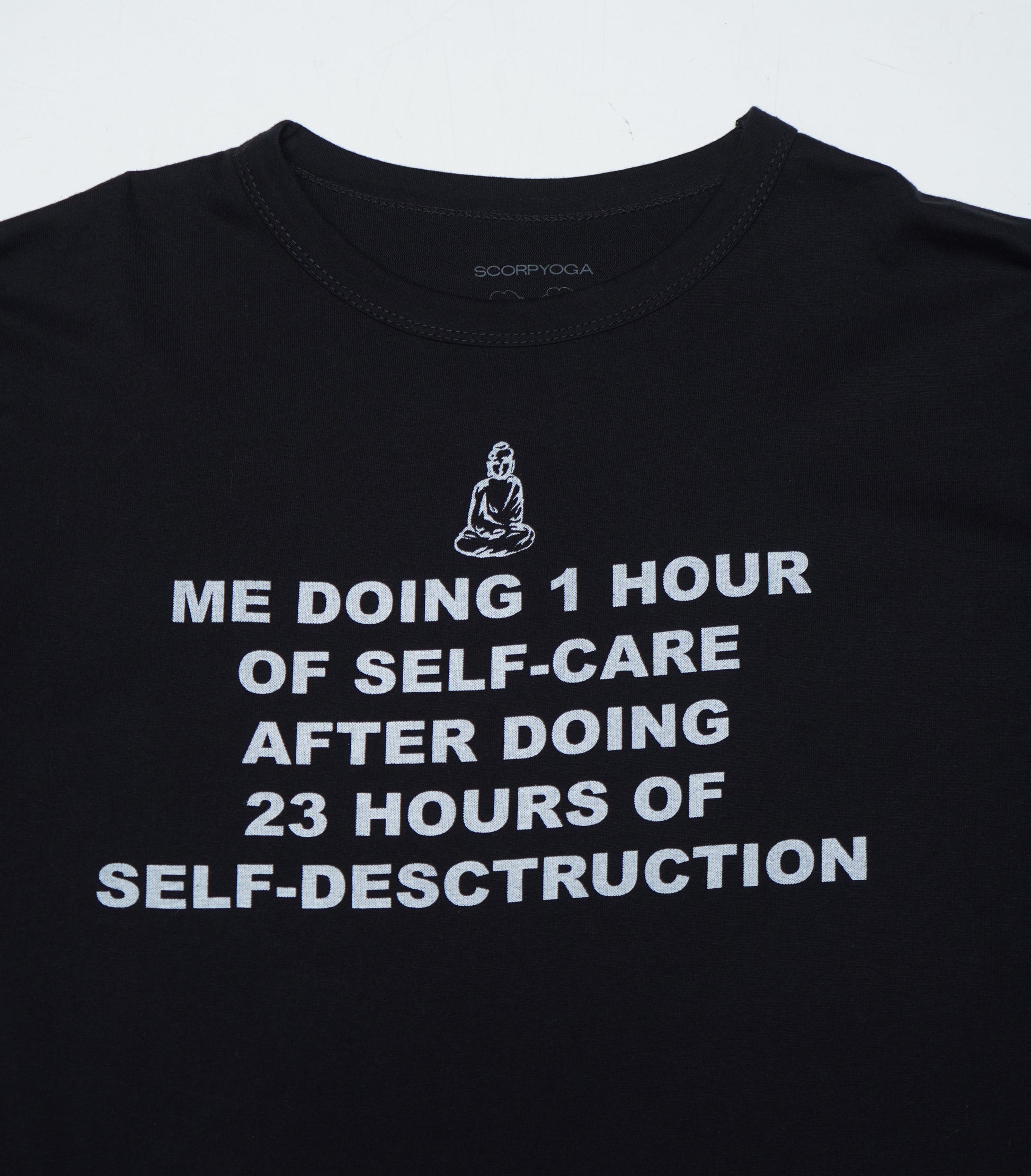 Black t-shirt with white text and a Buddha illustration on a light gray background