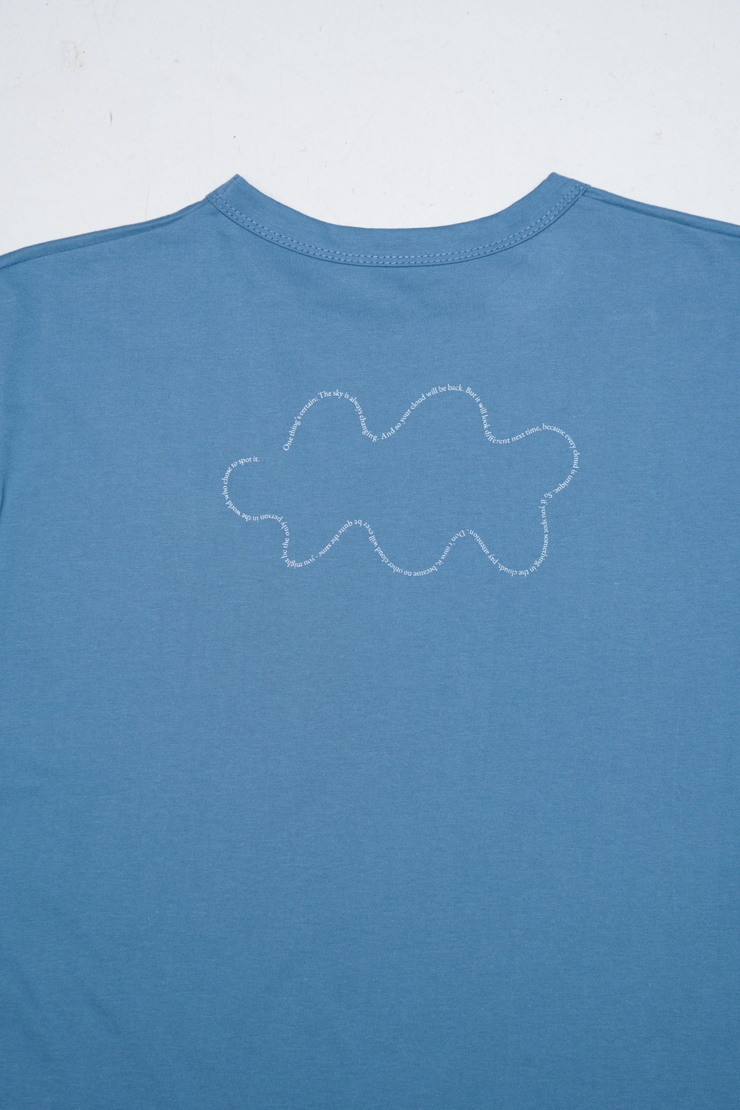 Blue t-shirt with a white cloud design on a light gray background