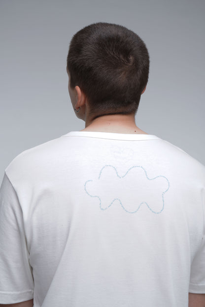 Person wearing a white t-shirt with a cloud design on the back against a gray background