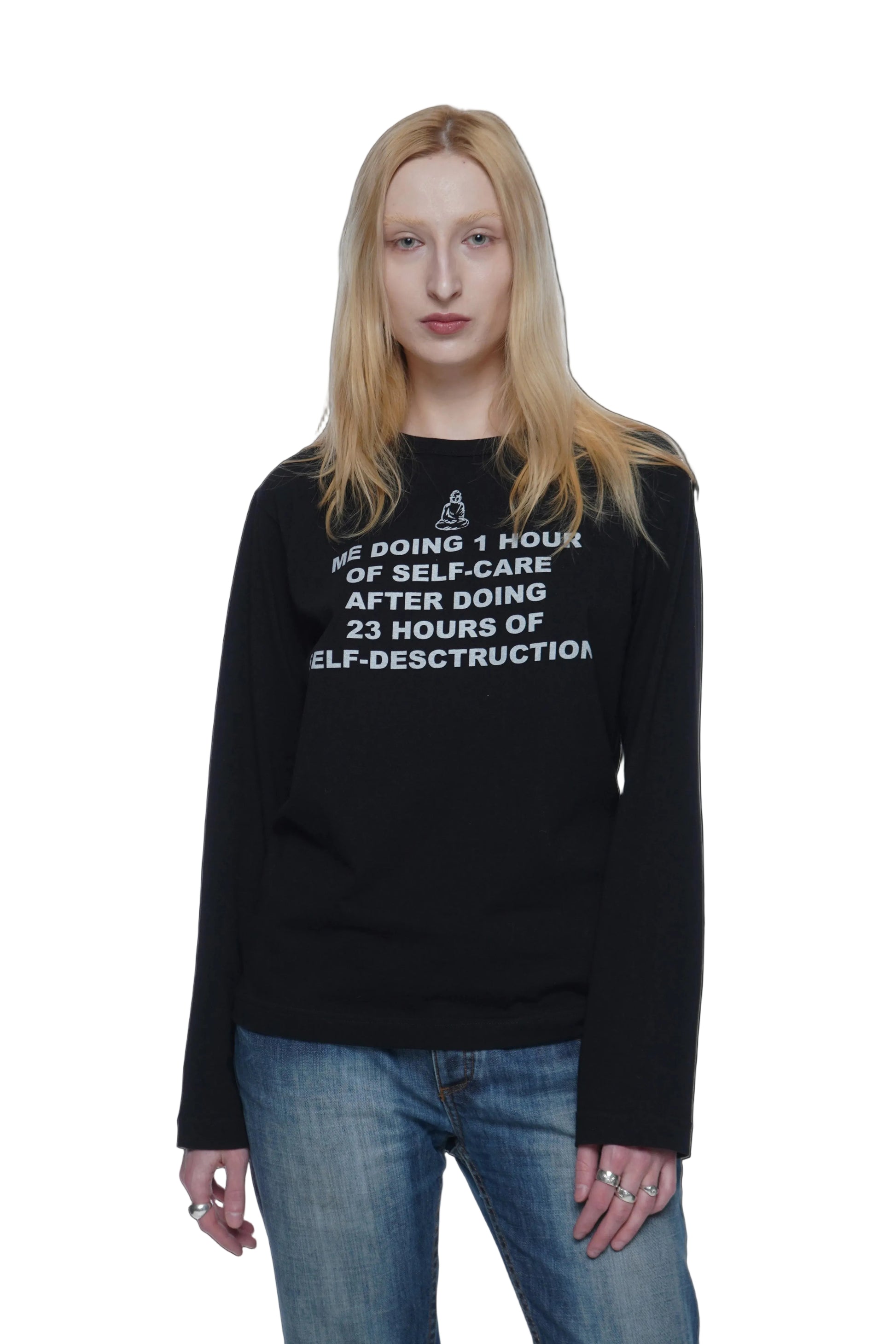 Person wearing a Black graphic long sleeve shirt with silkscreen print reading "me doing 1h of selfcare after doing 23h of self-destruction" on a white background